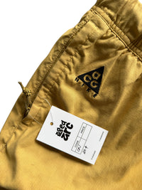 Aged Arc mustard yellow Nike ACG shorts with an elastic waistband and drawstring detail.